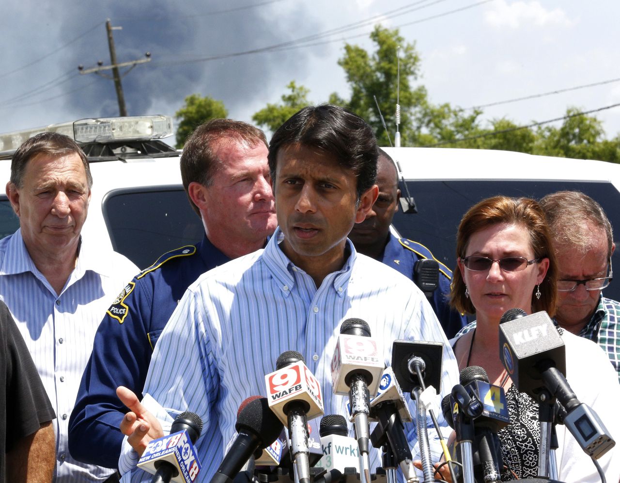 Smoke rises behind Louisiana Gov. Bobby Jindal as he talks about the explosion.