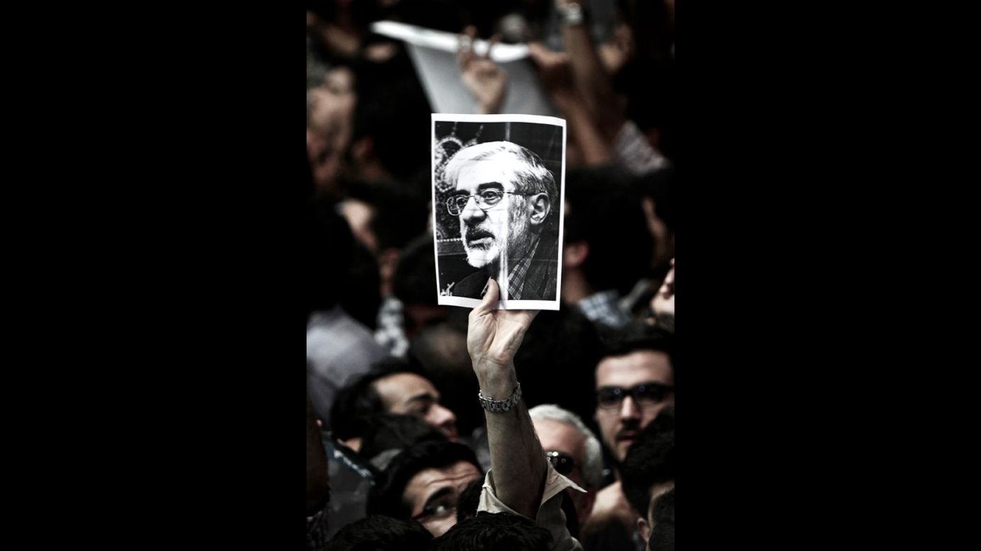 A man holds a portrait of opposition leader Mir Hossein Mousavi, who has been <a href="http://www.cnn.com/2011/WORLD/meast/02/19/iran.opposition.leader/index.html">under house arrest since February 2011</a>, during a campaign rally for Aref in Tehran on June 10.
