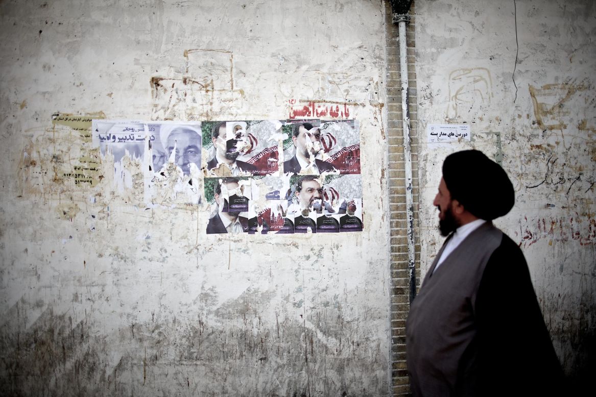 An Iranian clergyman walks past campaign posters on June 9 in Qom, south of the capital city of Tehran.