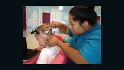Poli Rodriguez removes a nit from 9-year-old Emma's hair at a Pasadena, California, salon.