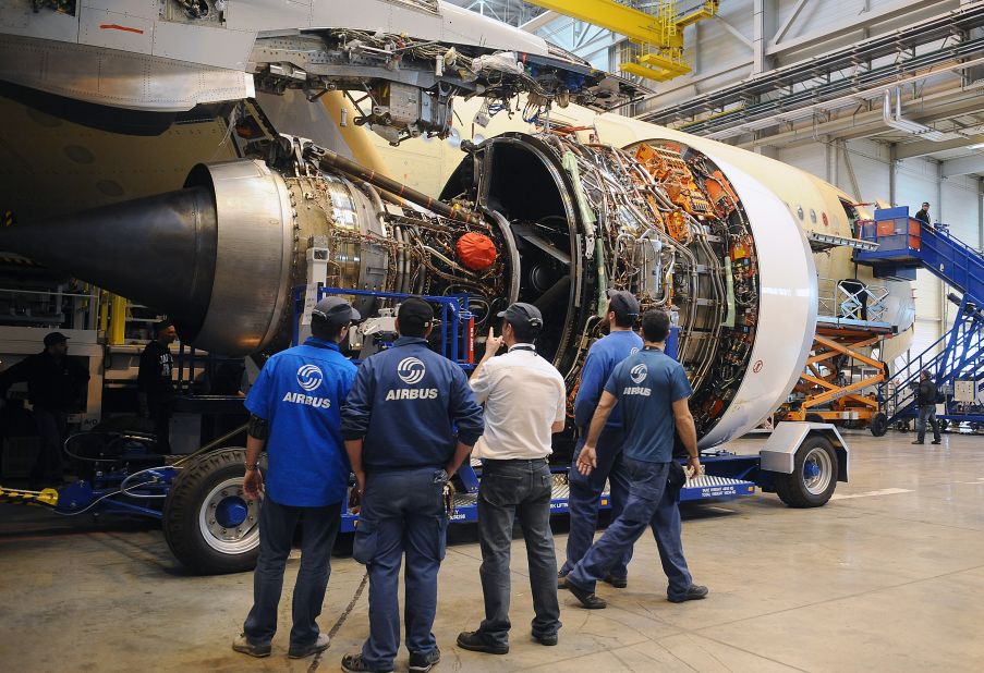 Technicians look at a Rolls-Royce jet engine, provided by UTC Aerospace Systems (formerly known as Goodrich), as they work on an A350-900 Airbus plane at the European aircraft maker's production plant in Toulouse. 