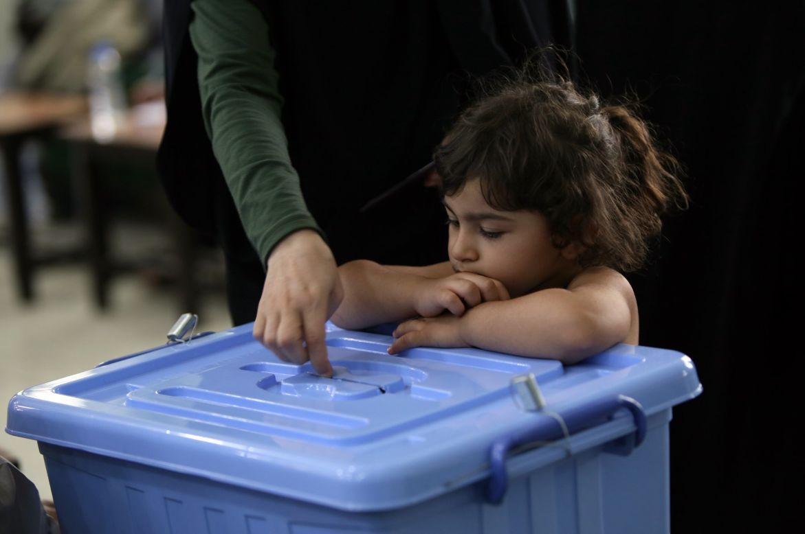 A girl watches a woman cast her ballot on June 14.