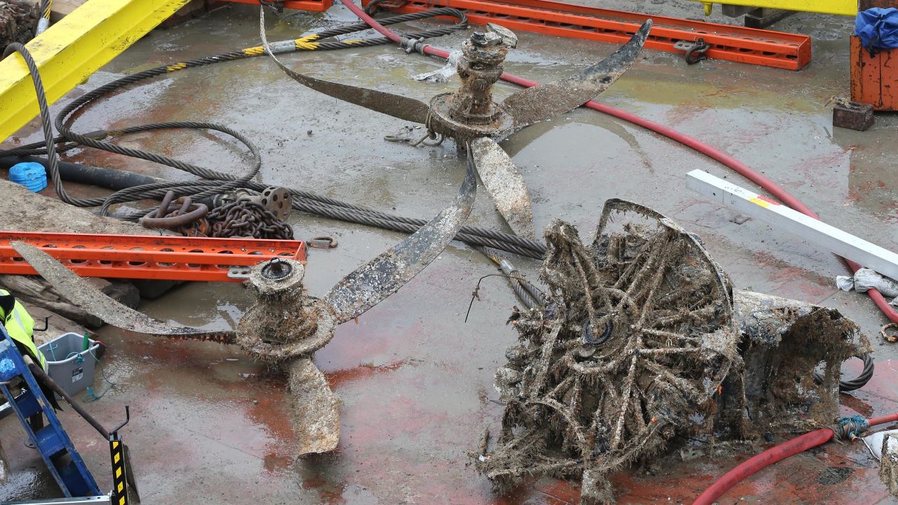 Seawater-damaged engine parts and propellers of the aircraft sit on a salvage barge.