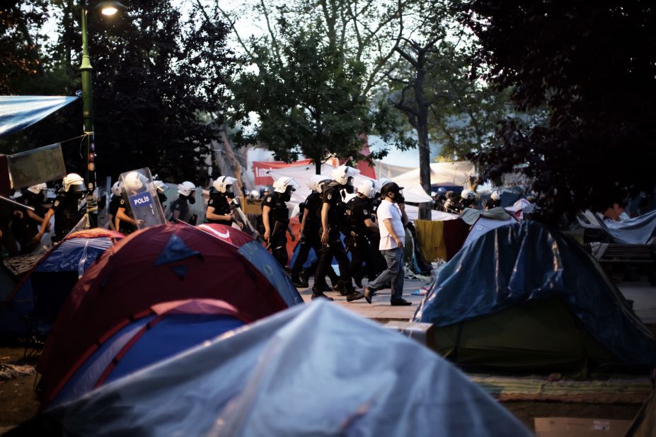 Riot police move in a line through the tent camp on June 15. 