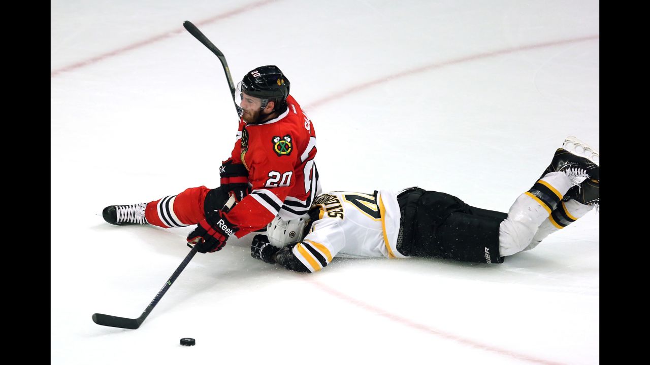 Brandon Saad of the Chicago Blackhawks falls to the ice on top of Dennis Seidenberg of the Boston Bruins.