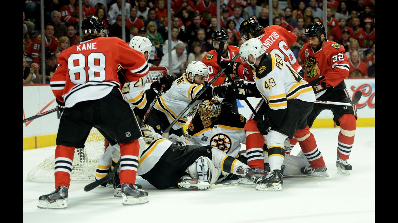 Goalie Tuukka Rask of the Boston Bruins attempts to follow the puck as players from the Bruins and Chicago Blackhawks shove each other in front of the net.