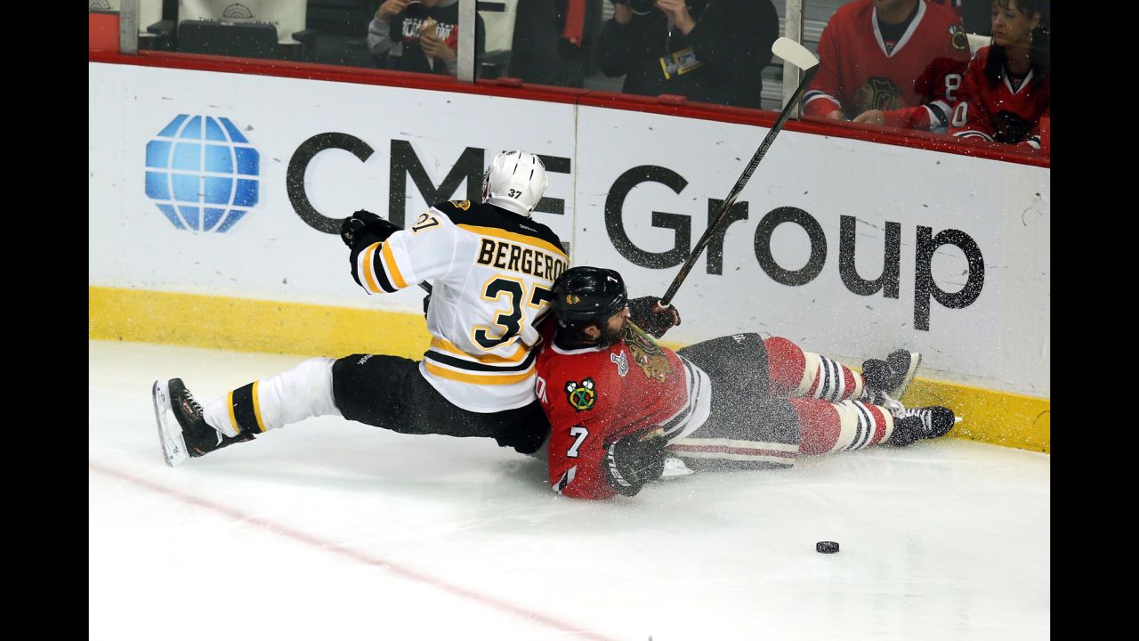 Patrice Bergeron of the Boston Bruins and Brent Seabrook of the Chicago Blackhawks slide down the ice into the boards.