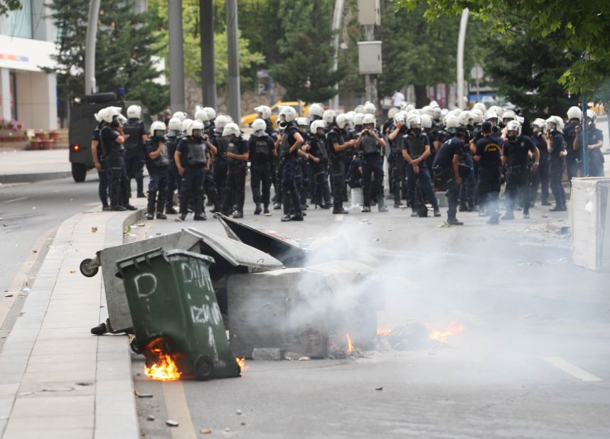 Trash containers burn in front of riot police forces in Ankara, Turkey, on June 16.