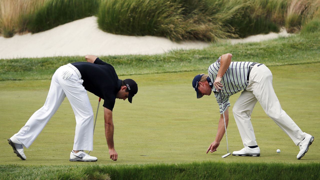 Charl Schwartzel and Steve Stricker examine the green during the final round.