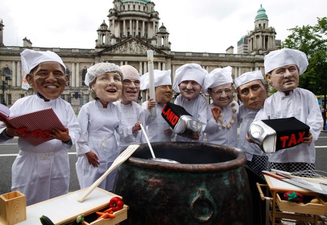 Oxfam charity volunteers wearing masks depicting the G8 leaders stand around a large cauldron outside City Hall in Belfast on June 16 to draw attention to the issue of world hunger.