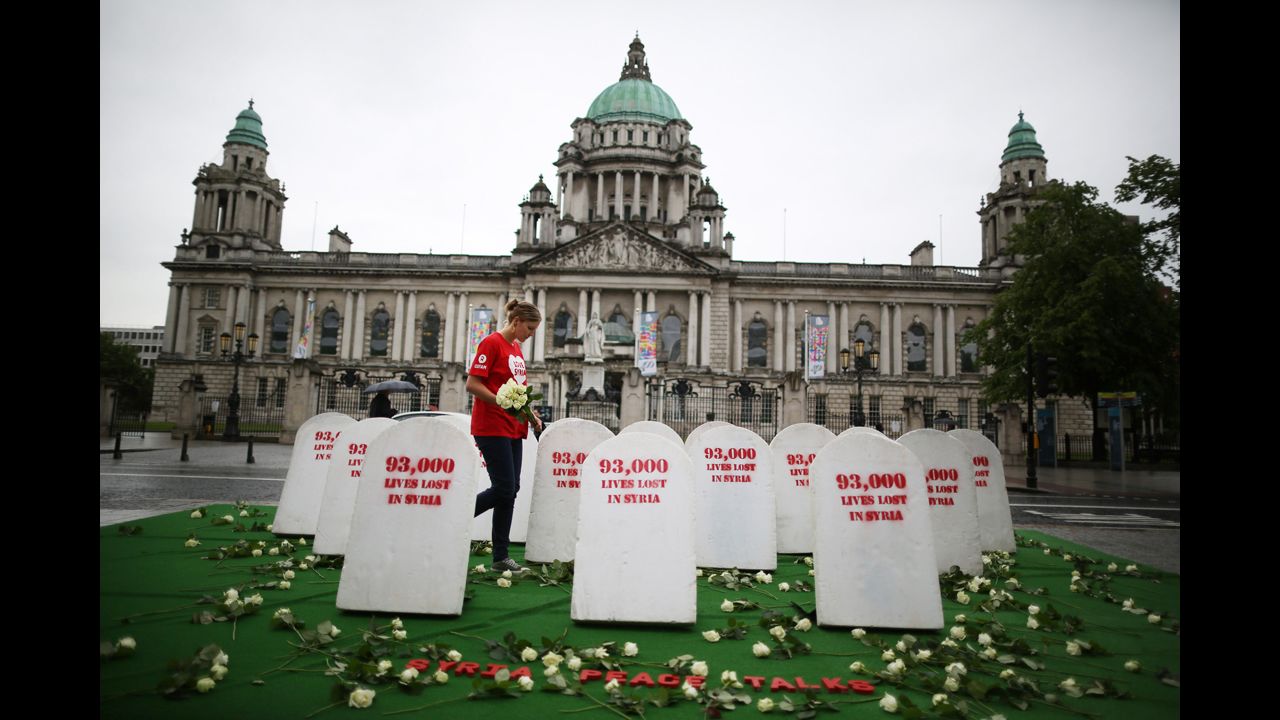 An Oxfam worker walks between mock gravestones on June 17 in Belfast. The gravestones represent the thousands of people killed in Syria's civil war. 