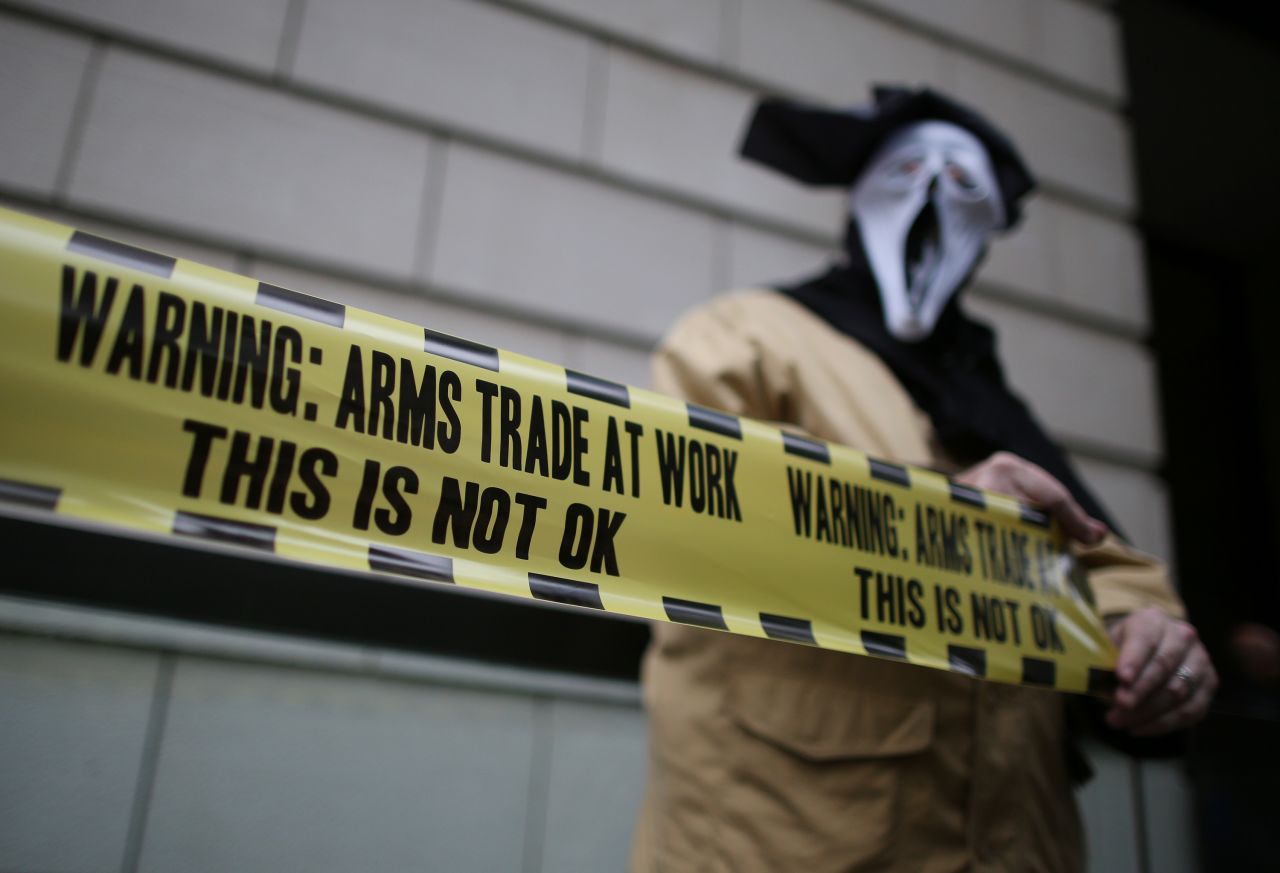 A masked demonstrator protests outside arms manufacturer BAE Systems on Wednesday, June 12, in London.
