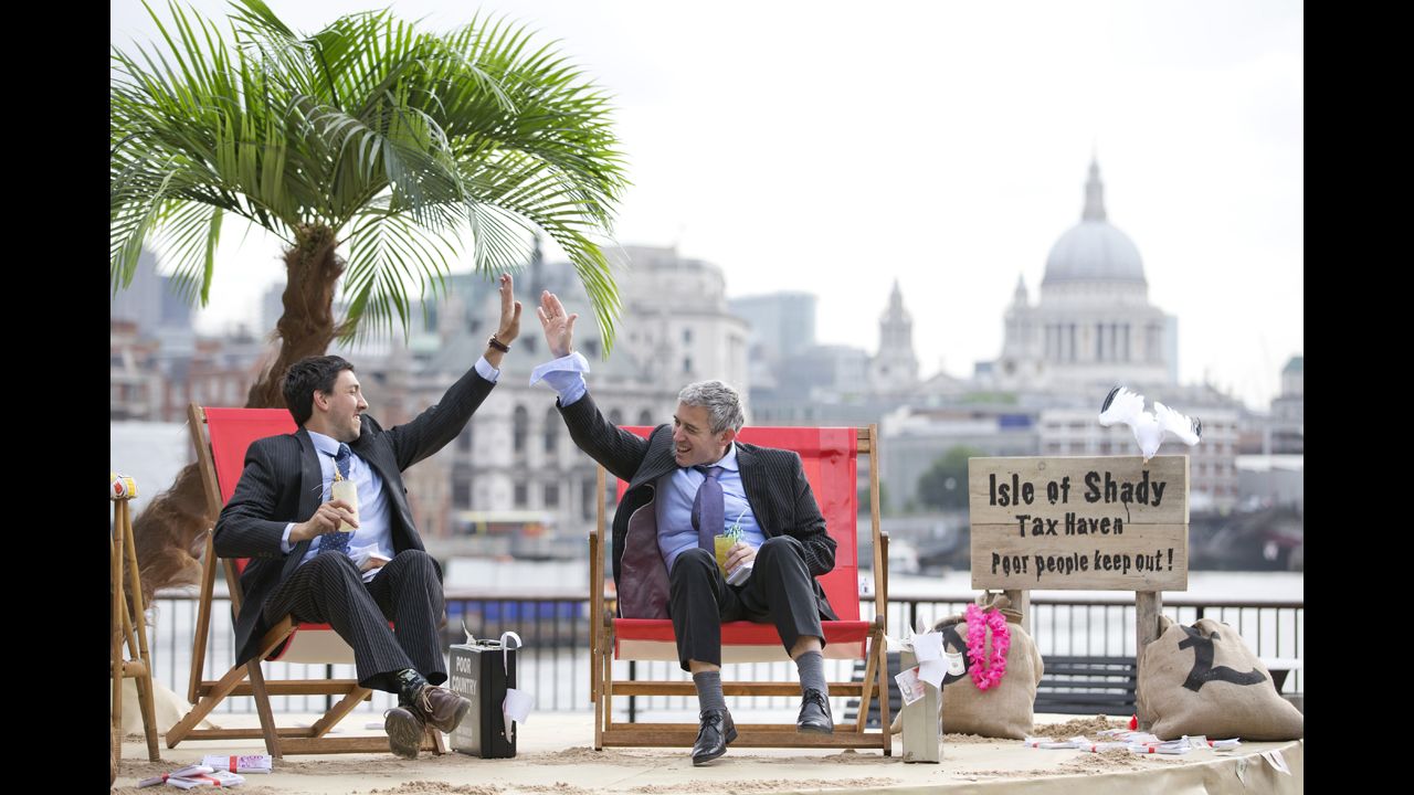 Protesters in suits high-five on the set of their "Isle of Shady Tax Haven" in London on Friday, June 14.