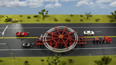 A model of the truck that will be used to transport the Muon g-2 ring, placed on a streetscape for scale. The truck will be escorted by police and other vehicles when it moves from Brookhaven National Laboratory in New York to a barge, and then from the barge to Fermi National Accelerator Laboratory in Illinois.