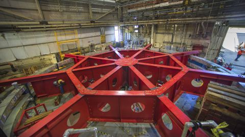 Crews work to attach the red stabilizing apparatus to the Muon g-2 rings at Brookhaven National Laboratory in New York in preparation for moving them over land and sea to Fermi National Accelerator Laboratory in Illinois. 
