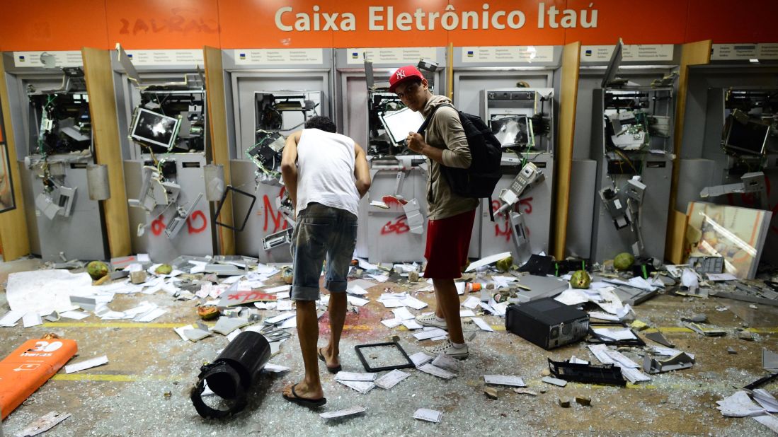 Two men look at smashed ATMs in Rio de Janeiro on June 17.
