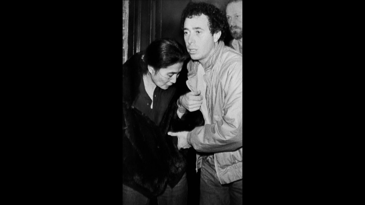 Yoko Ono is helped by David Geffen as she leaves Roosevelt Hospital after learning of the death of her husband.