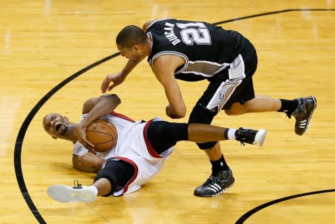 Chris Bosh of the Miami Heat falls with the ball as Tim Duncan of the San Antonio Spurs guards him.