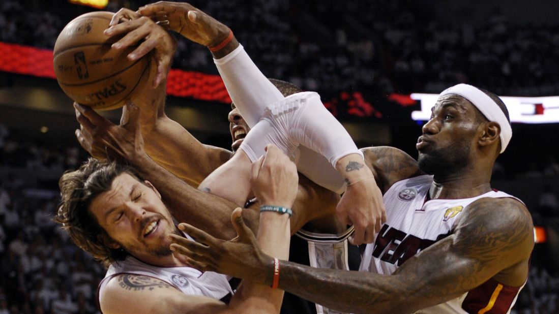 Mike Miller, left, and LeBron James of the Miami Heat vie for a rebound with Tim Duncan of the San Antonio Spurs.
