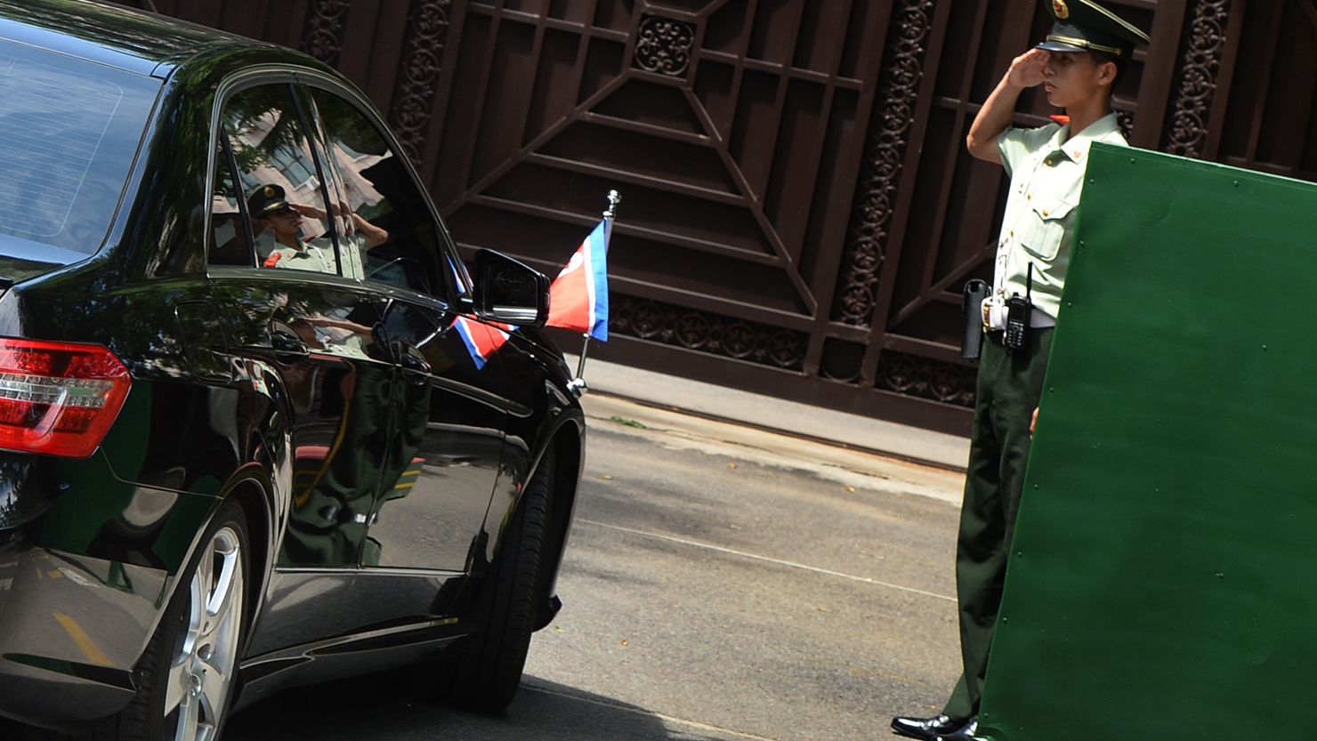 A Chinese officer salutes the car of North Korean officials as they return from talks in Beijing on June 19, 2013. 