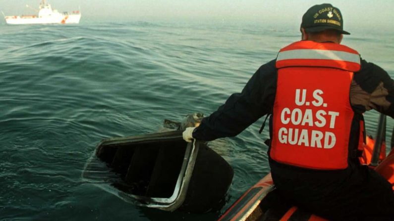 A member of the U.S. Coast Guard pulls a piece of wreckage from the waters on July 18, 1996.