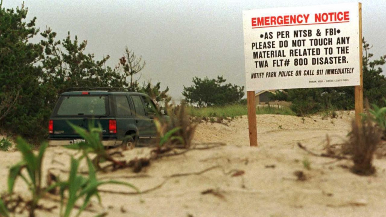 A warning sign on the dunes alerts beach-goers to watch for debris washed ashore at Smith's Point, Long Island, New York, on July 25, 1996.