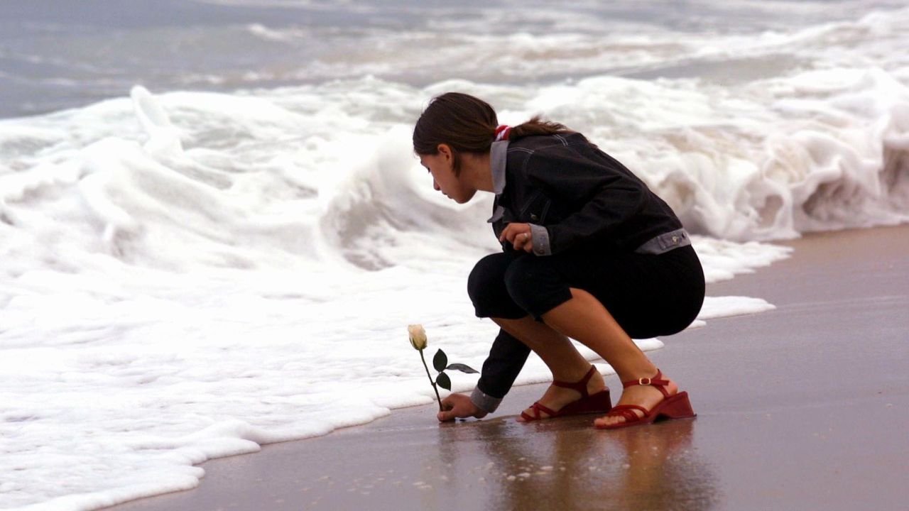 Antonella Naglieri, whose relatives Giuseppe Mercurio and Anna D'Alessandro were killed in the crash, places a rose in the surf after a memorial service at Smith Point Park in Shirley, New York, on July 17, 2001.