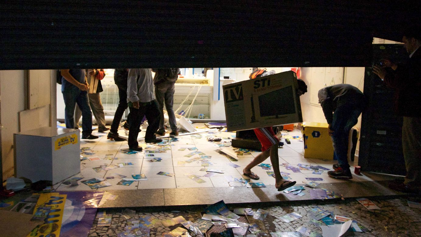 An unidentified person carries a television out of a store in Sao Paulo on June 18.