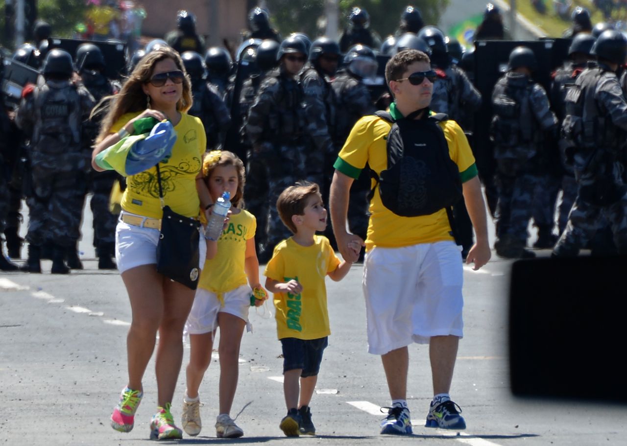 A family of four negotiate their way to the game as riot police prevent protesters from gaining access to Fortaleza's Castelao Stadium. 