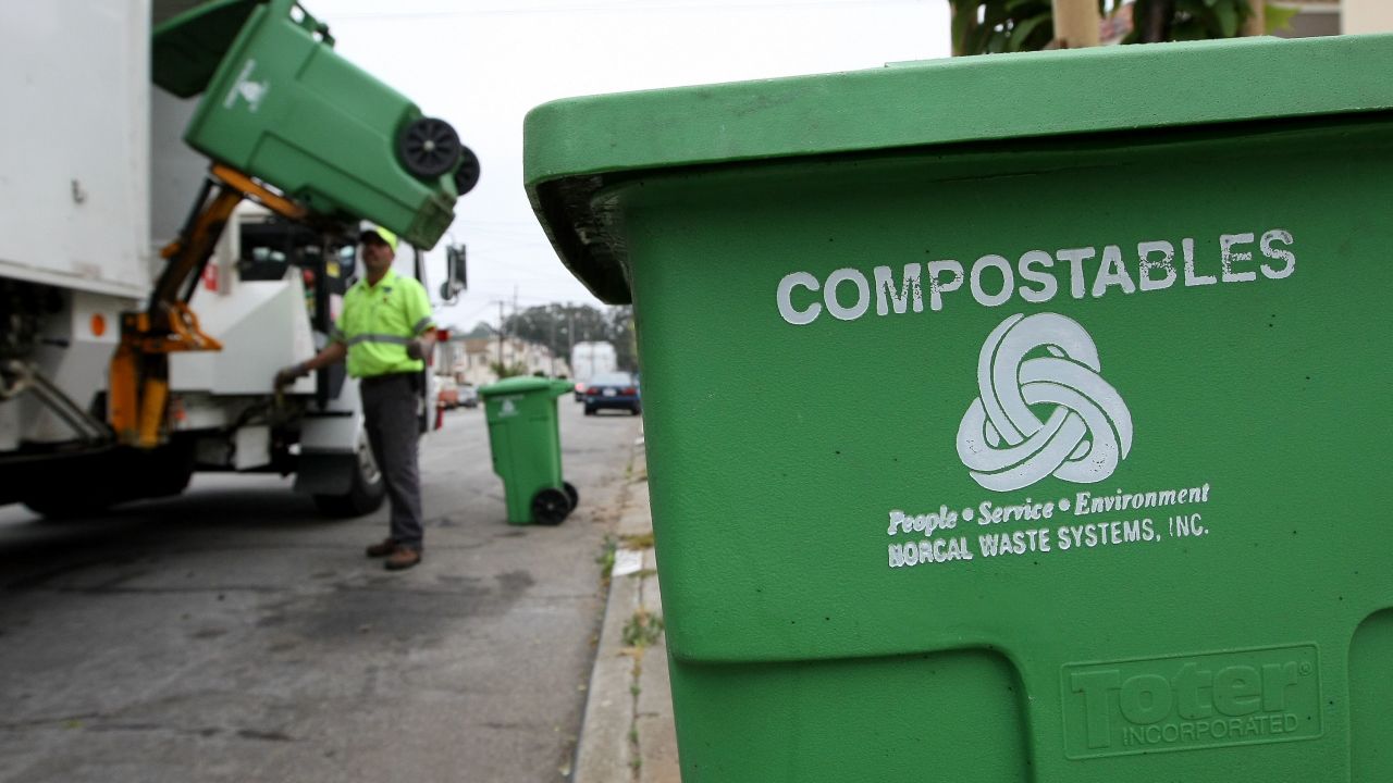 Manuel Vera dumps a bin with compostable materials into a truck while collecting recyclable materials in San Francisco.