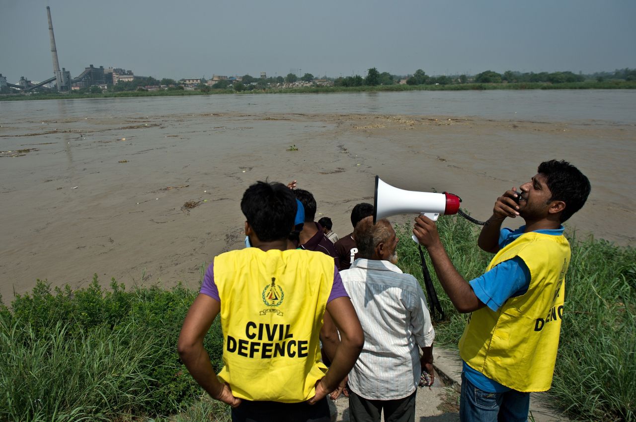 Civil Defence volunteers warn people against attempting to catch floating pumpkins, watermelons and other objects from the rising waters of the Yamuna River in New Delhi on June 19.