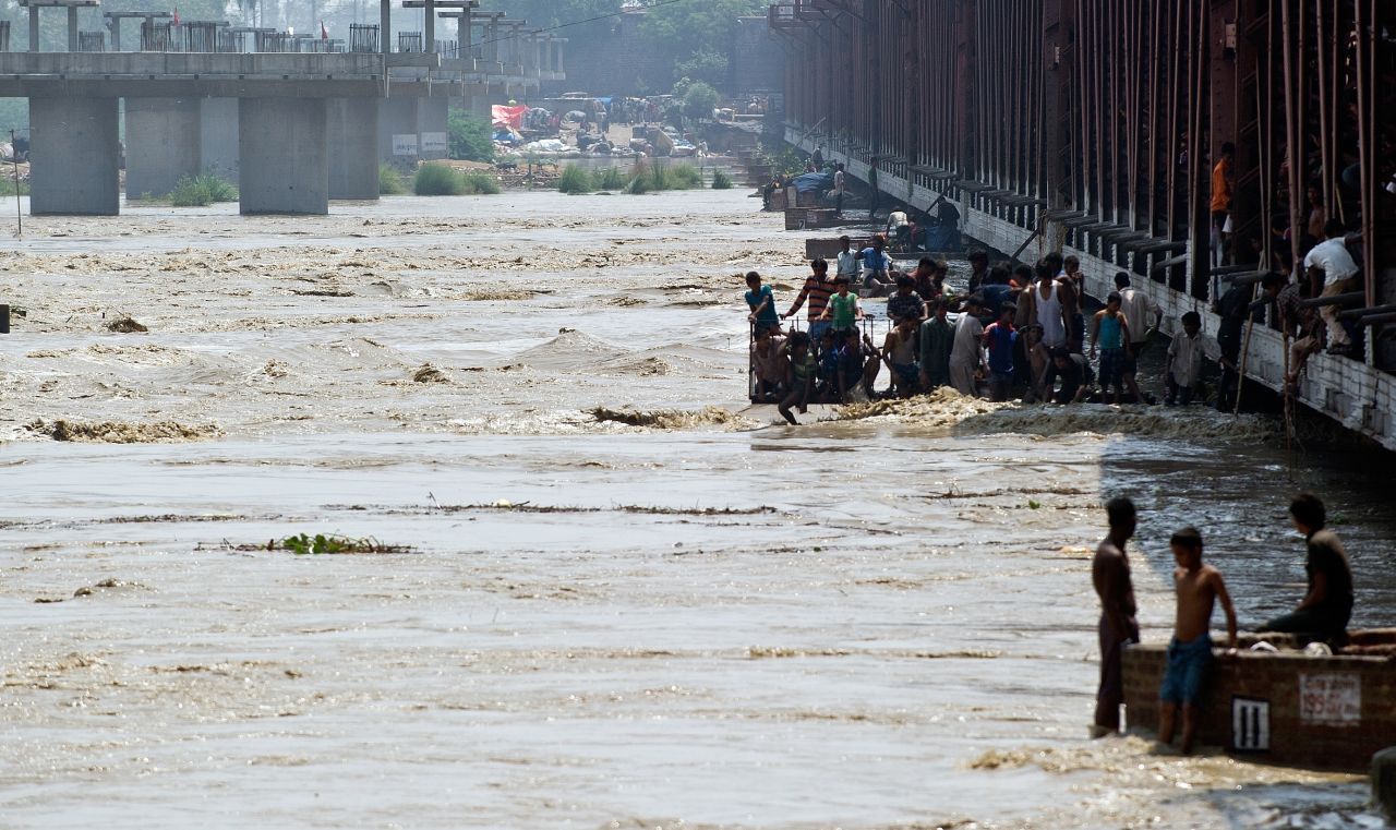 Men watch the rising waters of the Yamuna River from a bridge in New Delhi on June 19.