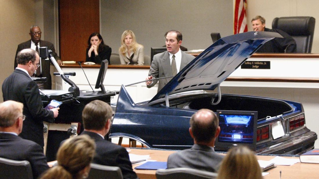 During the trial of Muhammad in November 2003, FBI visual information specialist Wynn Gregory Warren points to a hole cut in the trunk of a Chevrolet Caprice. The suspects had used the vehicle as a rolling sniper's nest, prosecutors said.