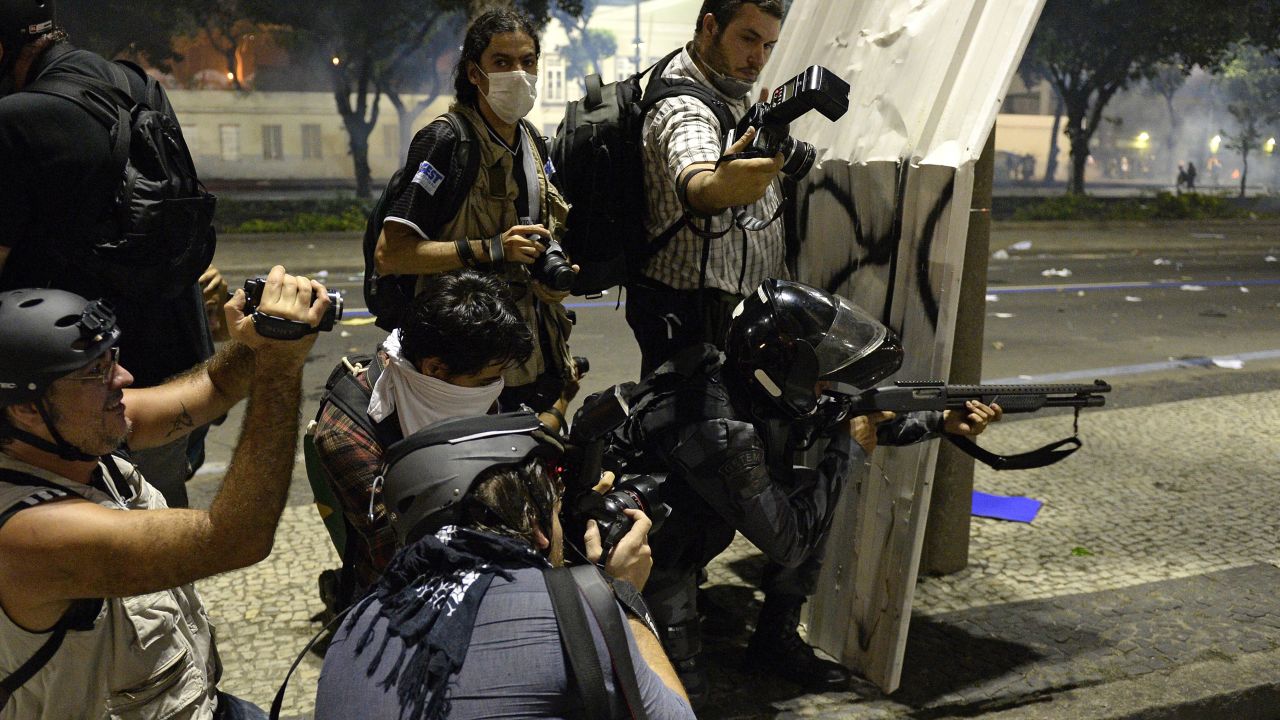 Photographers wait for a riot police officer to fire rubber bullets on June 20 in Rio de Janeiro.