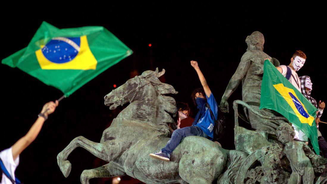Demonstrators stand on a statue in Niteroi outside Rio de Janeiro on Wednesday, June 19.