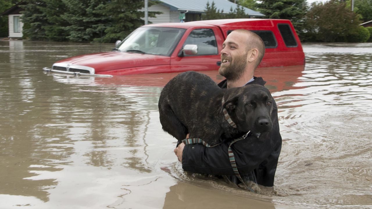 A man carries his dog to safety in High River, Alberta, on June 20.