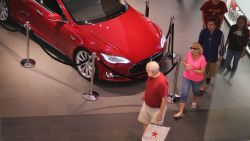 People walk out of a Tesla motor company dealership in the Dadeland Mall on June 6, 2013 in Miami.