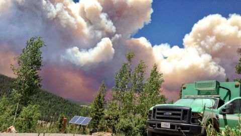 The West Fork Fire Complex burns 15 miles north of Pagosa Springs, on June 20, as a fire crew truck is parked nearby.