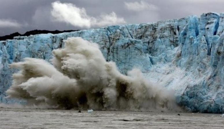 This is the moment a 75-meter chunk of ice falls off a towering glacier in Alaska. The tiny speck waiting in the water to surf the ensuing wave? That's Garrett McNamara.