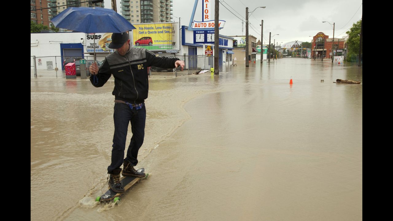 A man longboards through a flooded downtown street in Calgary on Friday, June 21.