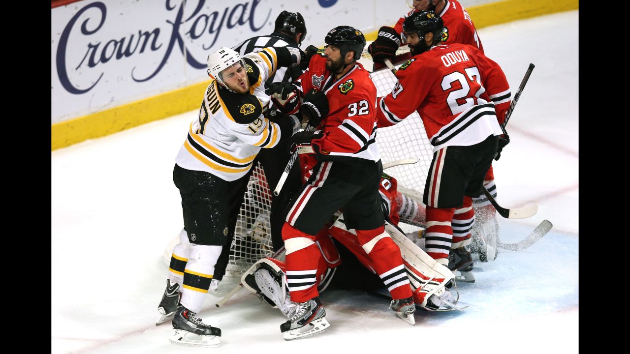 Tyler Seguin of the Bruins and Michal Rozsival of the Blackhawks push each other in front of the net.