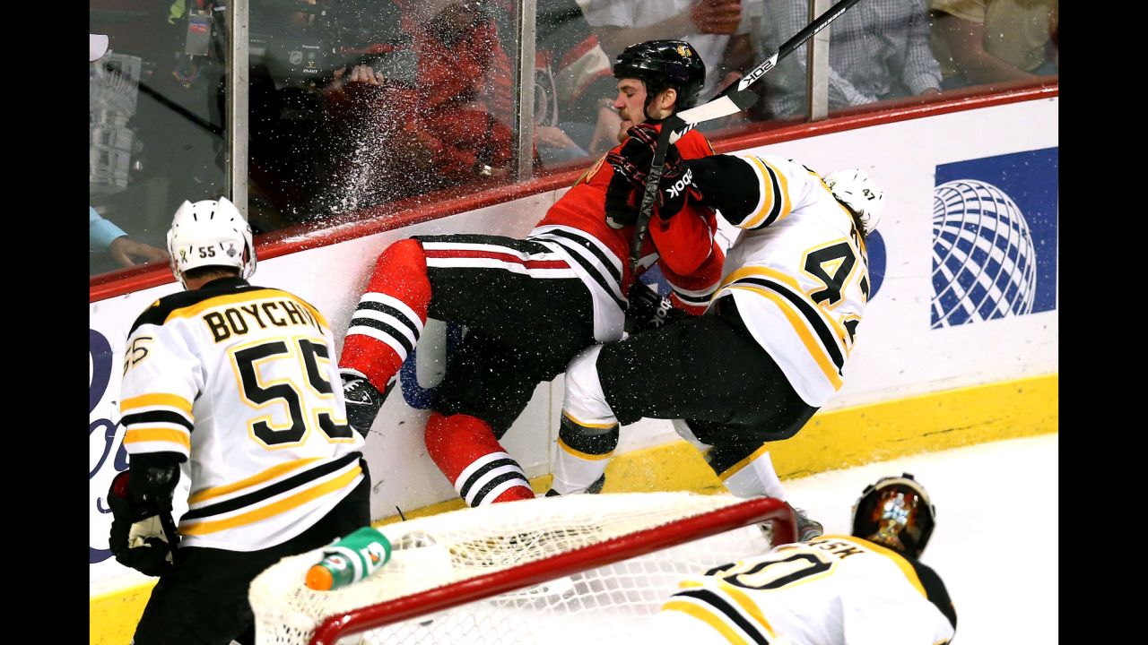 Andrew Shaw of the Chicago Blackhawks is pulled down by Torey Krug of the Boston Bruins.