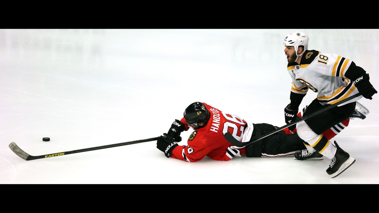 Michal Handzus of the Chicago Blackhawks dives for the puck against Bruin Nathan Horton.