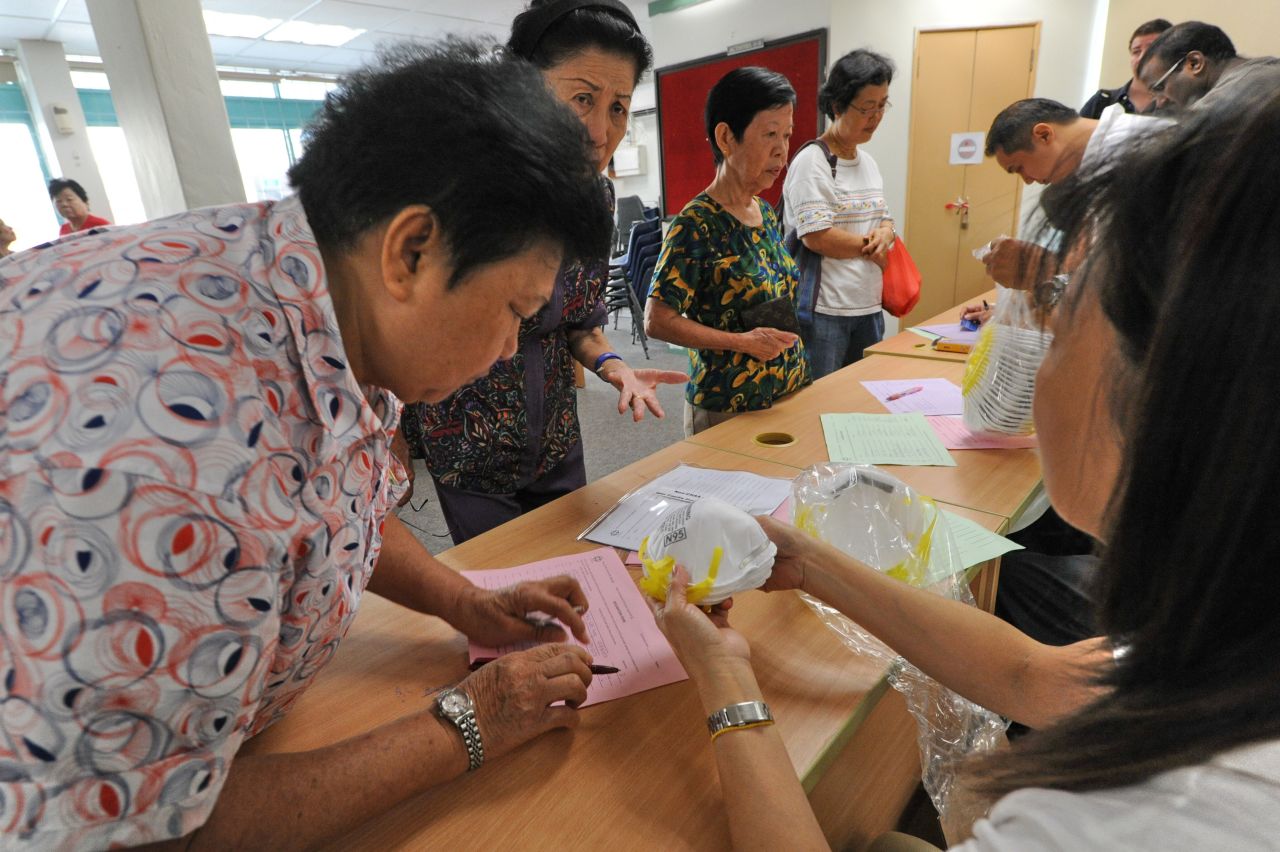 Elderly people sign up to collect face masks at the community centre for the low income in Singapore on June 22, 2013.
