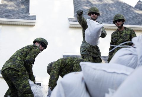 Canadian Armed Forces soldiers from the Calgary Highlanders pile sandbags to protect the Inglewood neighborhood in Calgary on June 22.