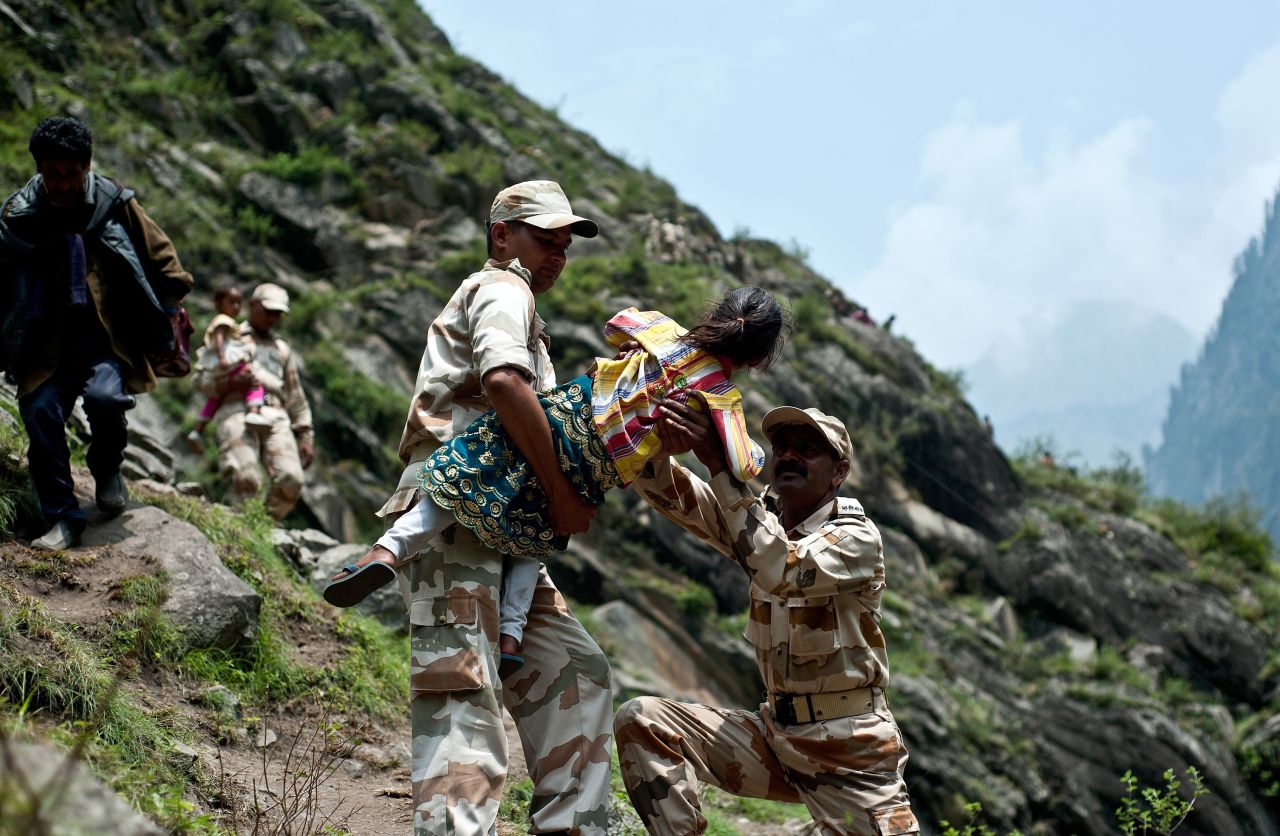 Police carry a child during efforts to help stranded Indian pilgrims on June 23 after a section of road was washed away in Govindghat.