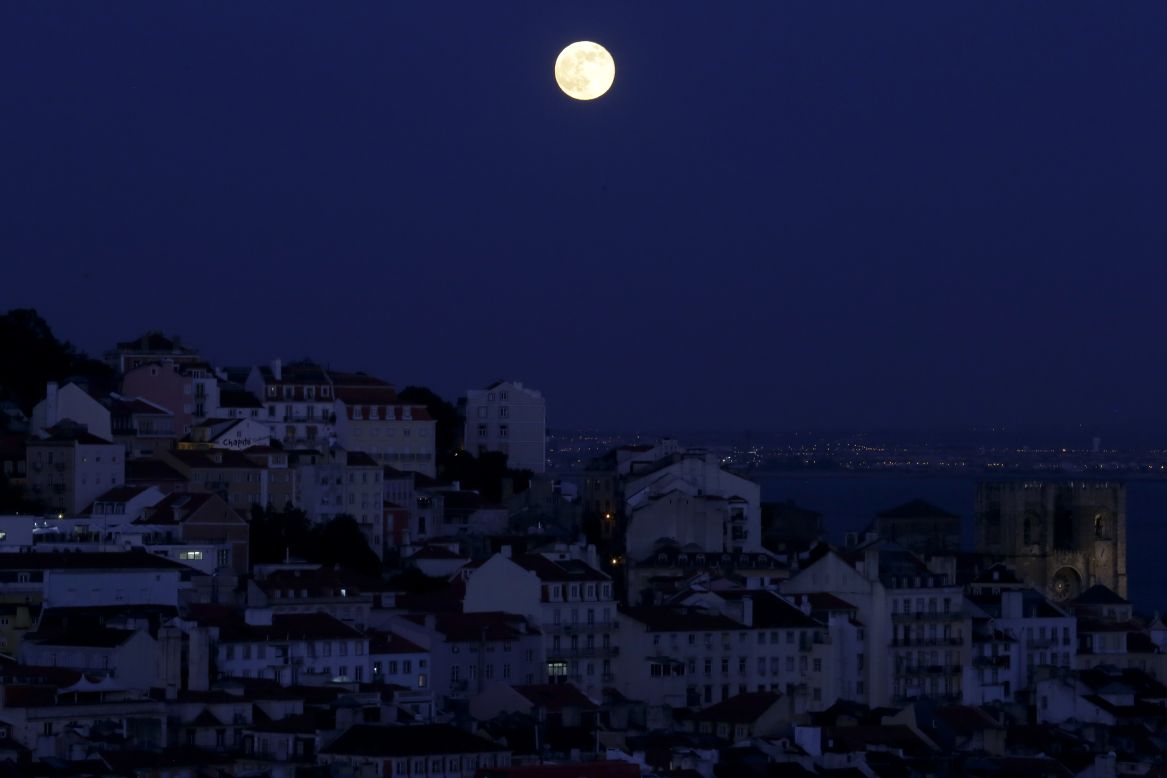 The full moon rises over Lisbon, Portugal, on June 23.
