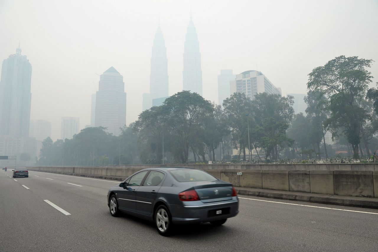 Motorists drive as haze shrouds Malaysia's landmark Petronas Twins Towers in Kuala Lumpur on June 23. The Malaysian government declared a state of emergency on June 23 in two southern areas.