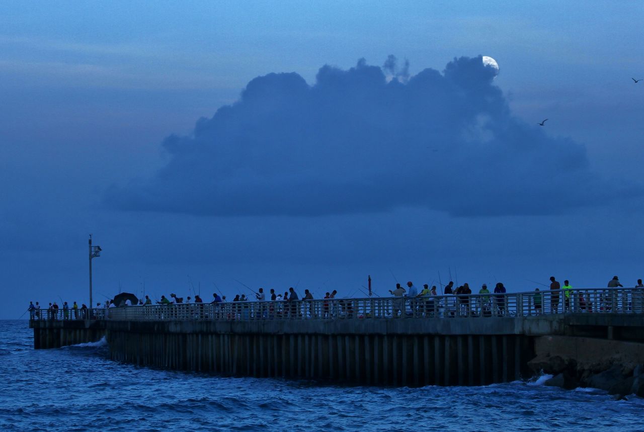 <a href="http://ireport.cnn.com/docs/DOC-993604">Billy Ocker</a> stood on the pier of the Sebastian, Florida, inlet, photographing the supermoon peeking through the thick clouds overhead. "The moon was late in its showing and I almost thought I might not be able to see it because of the clouds. But just when I was about to give up, the Sun went completely down and I could see the clouds starting to glow white and then the Supermoon," he said.