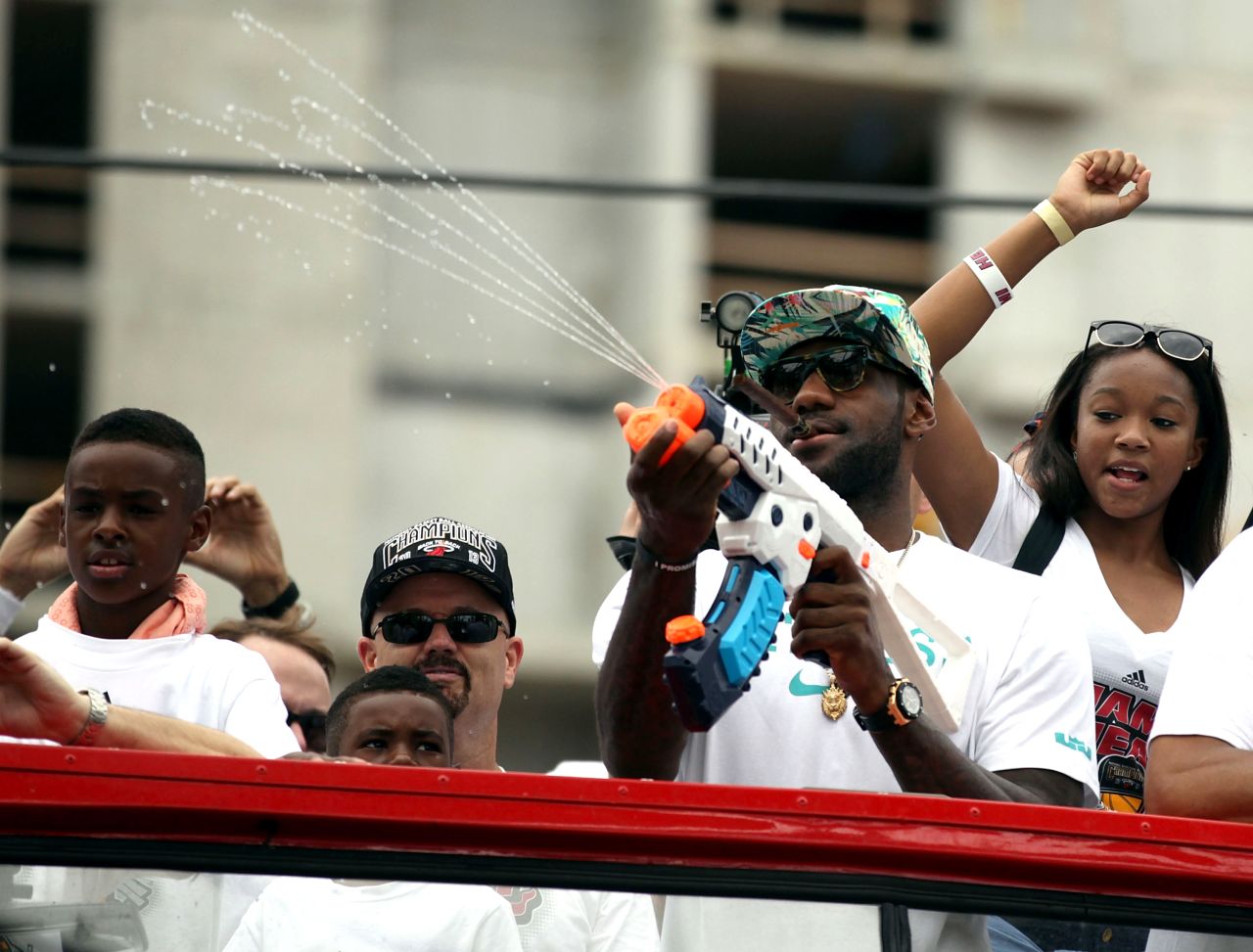 LeBron James sprays fans with a water gun from the top of a bus during the victory parade through the streets of Miami.
